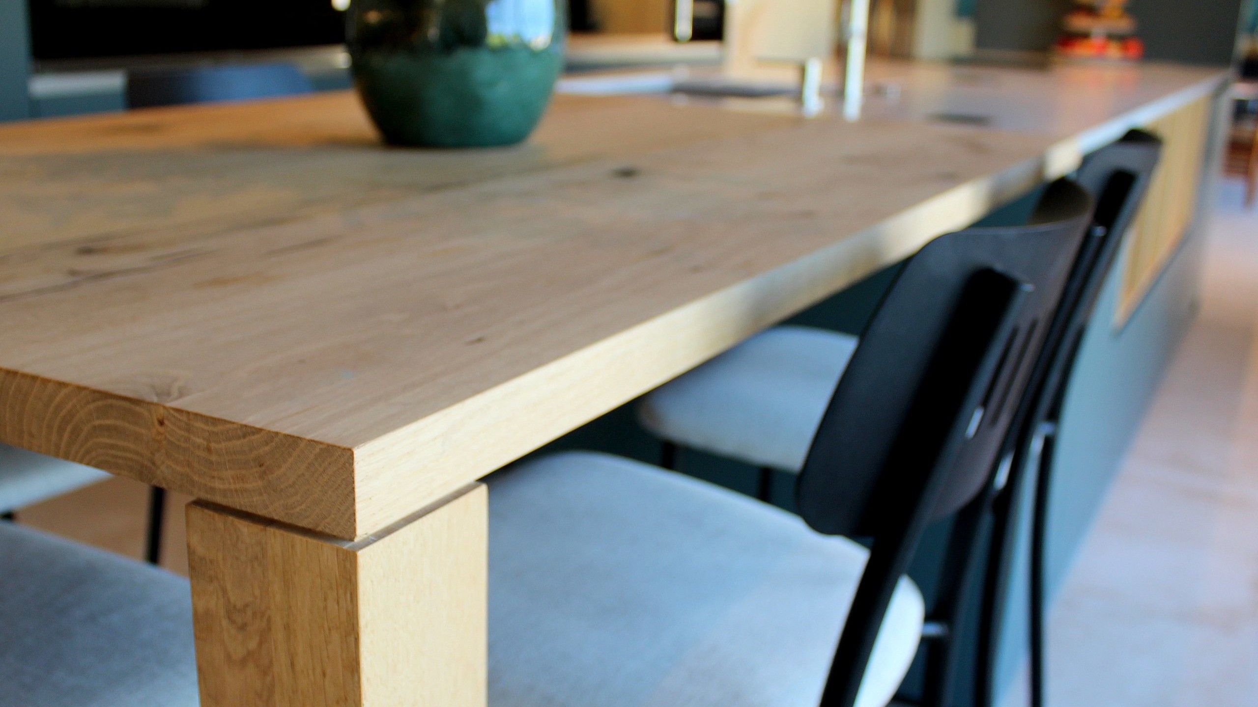 Vue d’ensemble d’une cuisine design avec façades vertes, îlot central en quartz et chêne massif, et mur panoramique végétal.