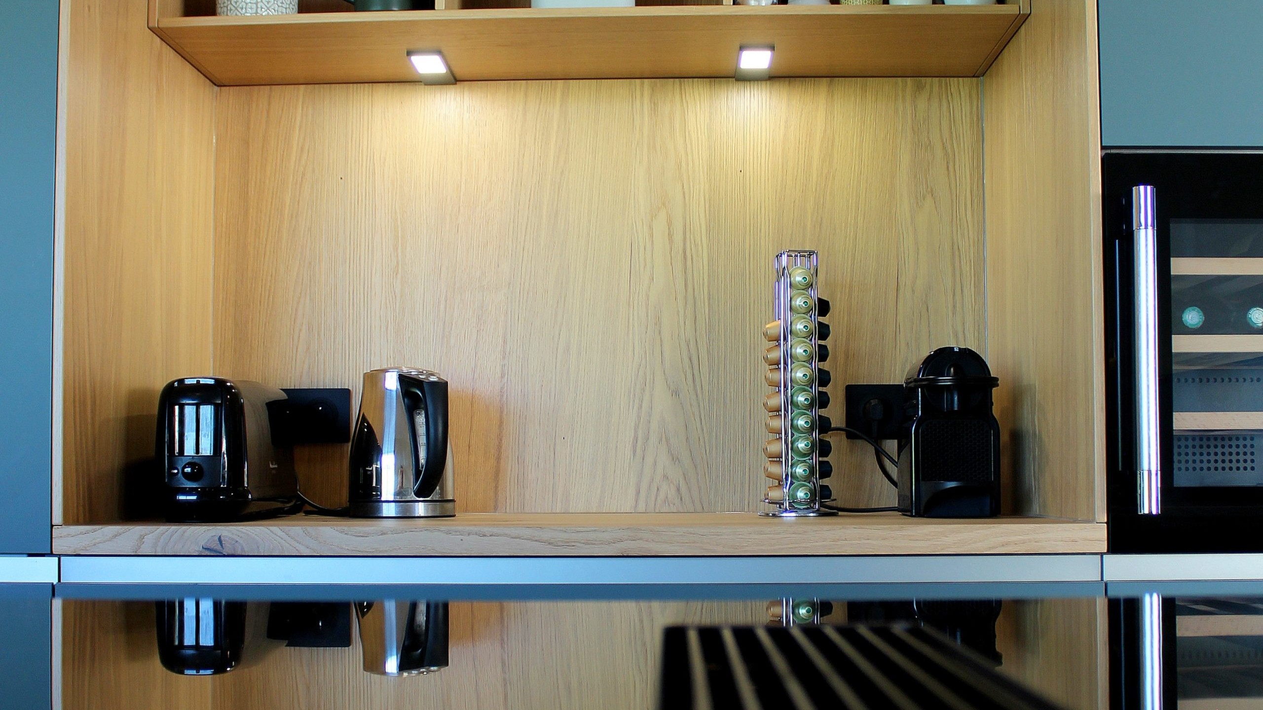 Vue d’ensemble d’une cuisine design avec façades vertes, îlot central en quartz et chêne massif, et mur panoramique végétal.