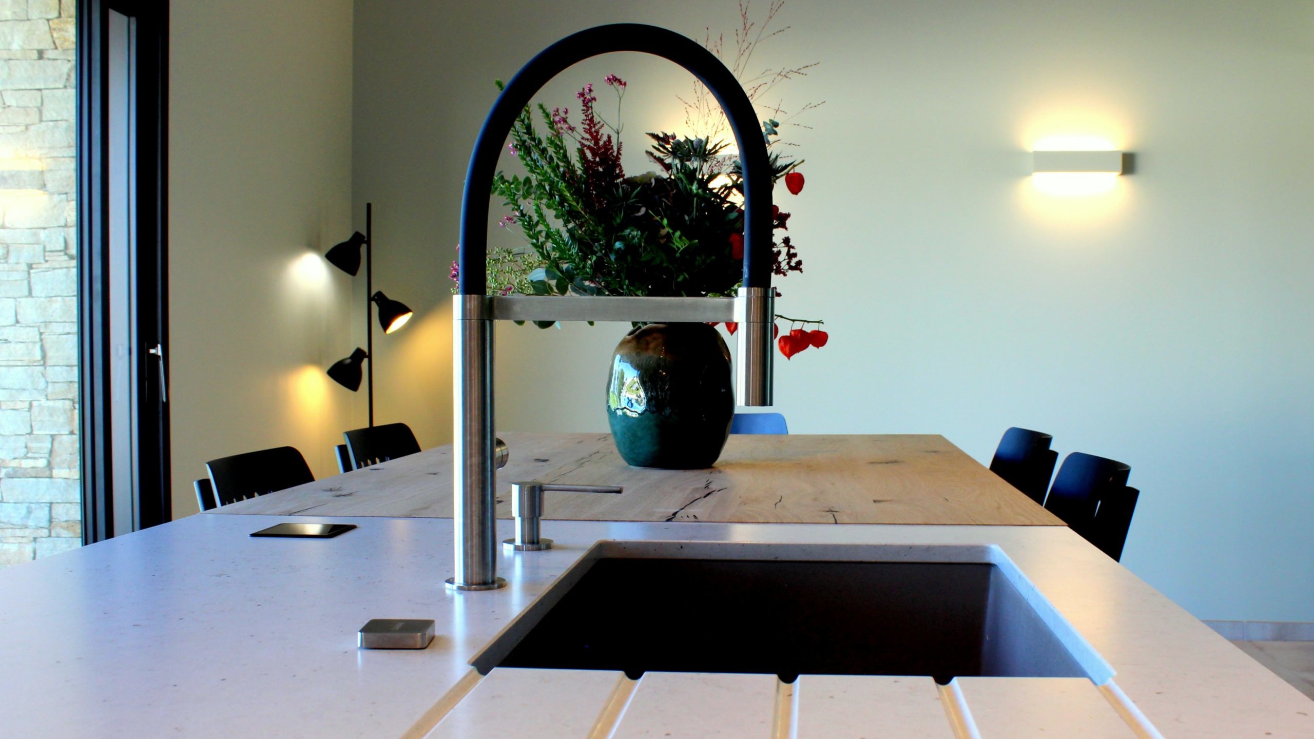 Vue d’ensemble d’une cuisine design avec façades vertes, îlot central en quartz et chêne massif, et mur panoramique végétal.