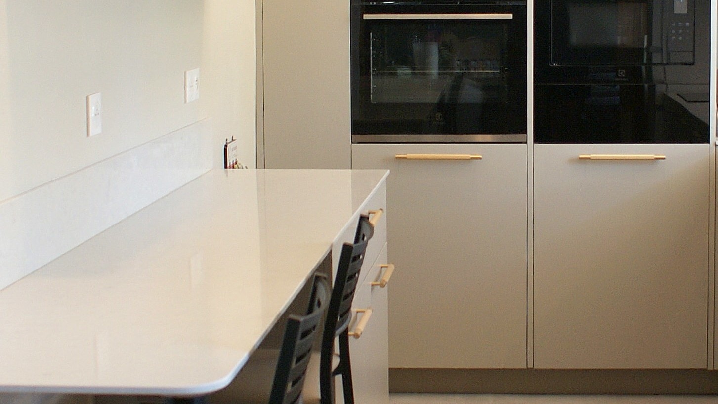 Cuisine contemporaine aux façades beige grisé et poignées dorées