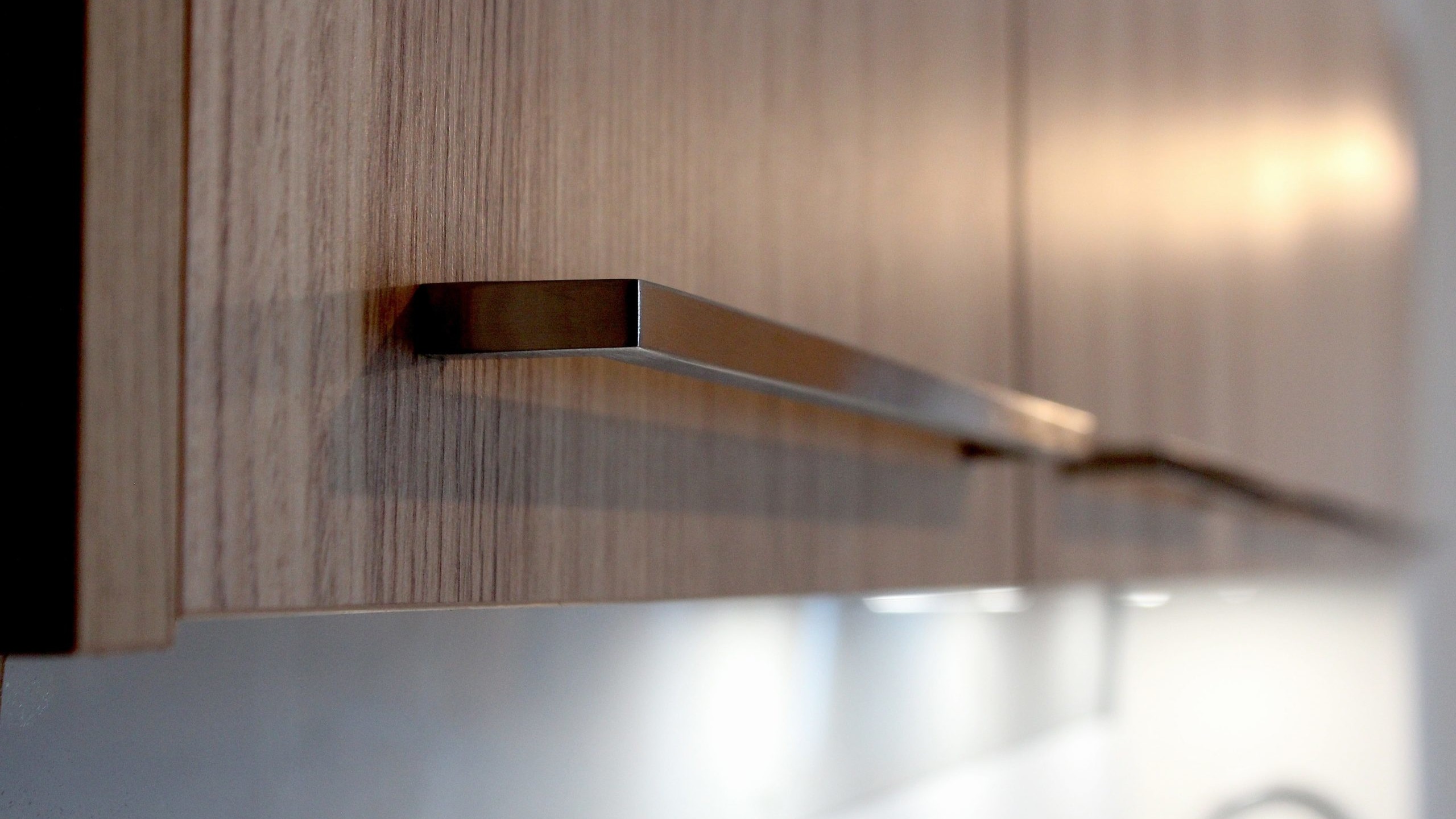 Cuisine moderne en placage bois clair avec plan de travail en quartz blanc, intégrée dans un intérieur en pierre à Nanteuil-en-Vallée.