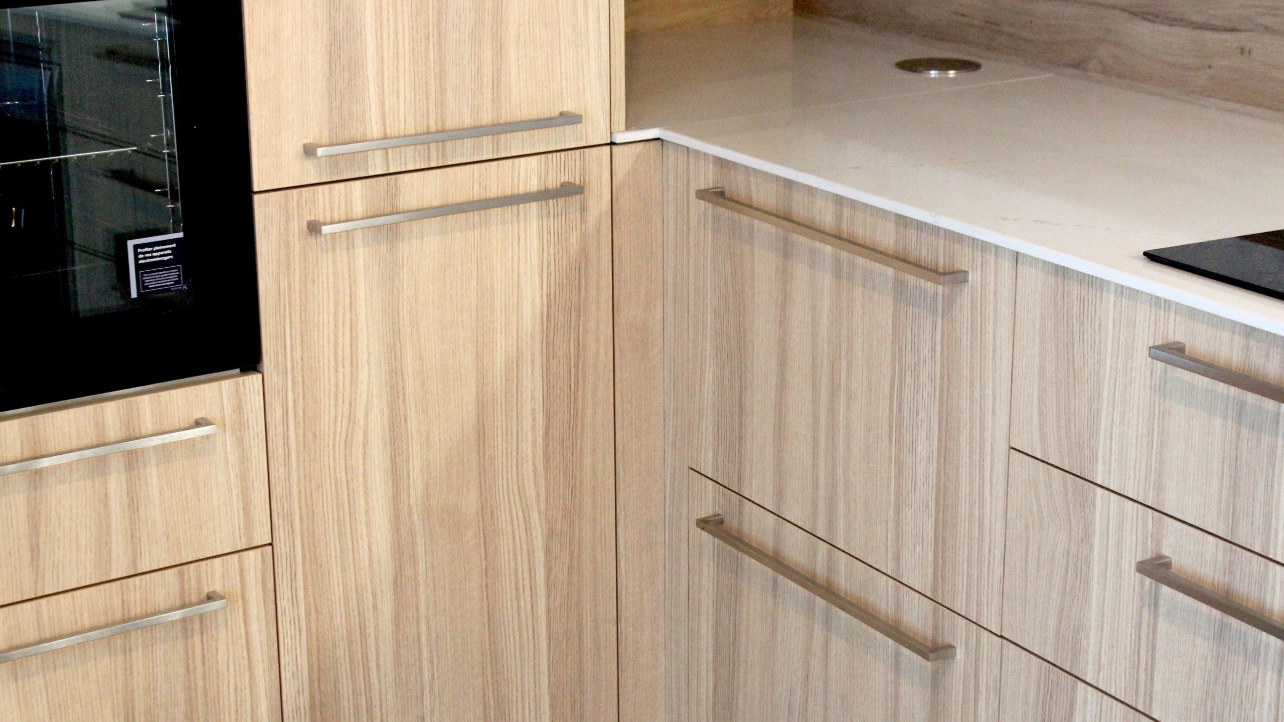 Cuisine moderne en placage bois clair avec plan de travail en quartz blanc, intégrée dans un intérieur en pierre à Nanteuil-en-Vallée.