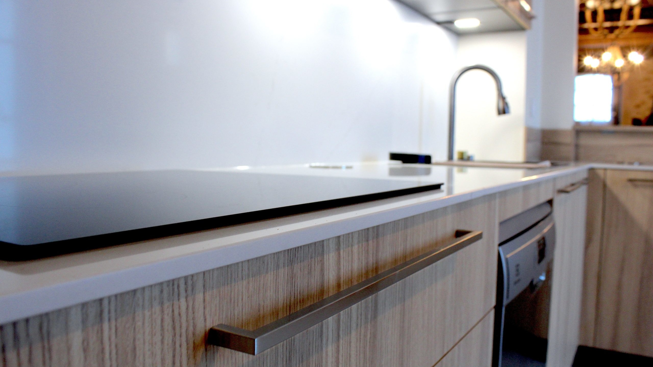 Cuisine moderne en placage bois clair avec plan de travail en quartz blanc, intégrée dans un intérieur en pierre à Nanteuil-en-Vallée.