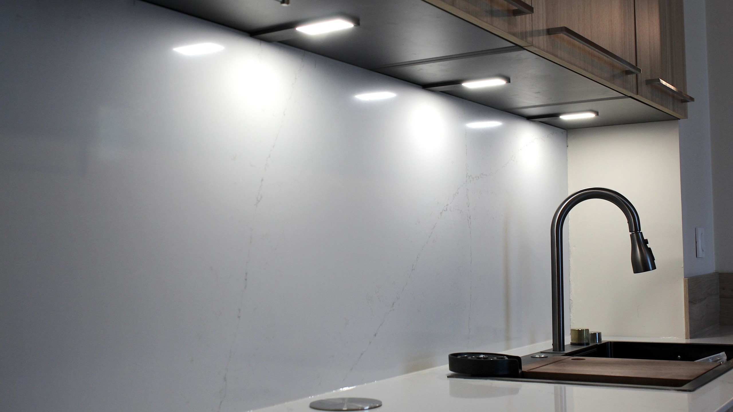 Cuisine moderne en placage bois clair avec plan de travail en quartz blanc, intégrée dans un intérieur en pierre à Nanteuil-en-Vallée.