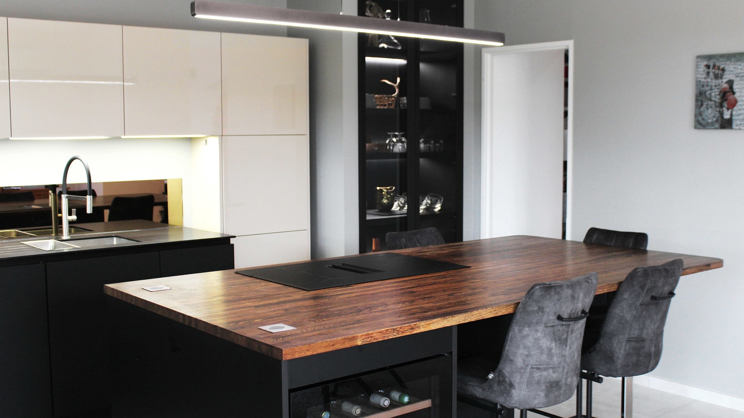 Cuisine moderne sur-mesure avec meubles Fenix noir mat, laque beige brillante, îlot central en bois wengé, plaque à induction avec hotte intégrée et crédence miroir bronze.