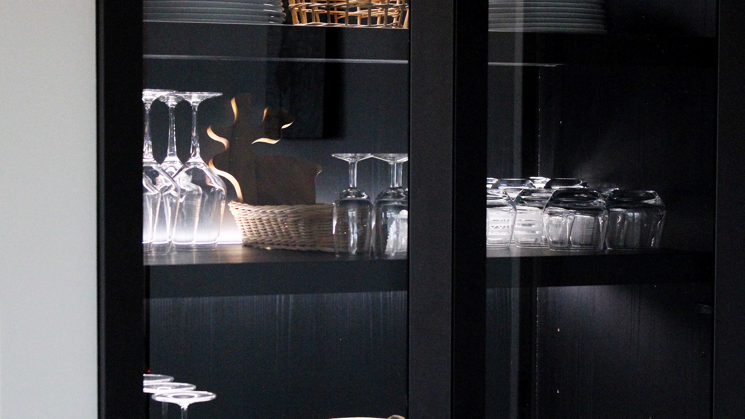 Cuisine moderne sur-mesure avec meubles Fenix noir mat, laque beige brillante, îlot central en bois wengé, plaque à induction avec hotte intégrée et crédence miroir bronze.