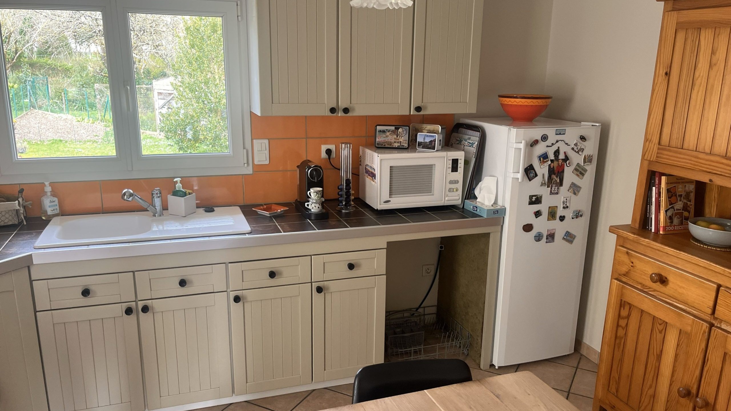 Cuisine grise avec poignée, faïence orange, buffet bois brut ou se trouve actuellement les colonnes.