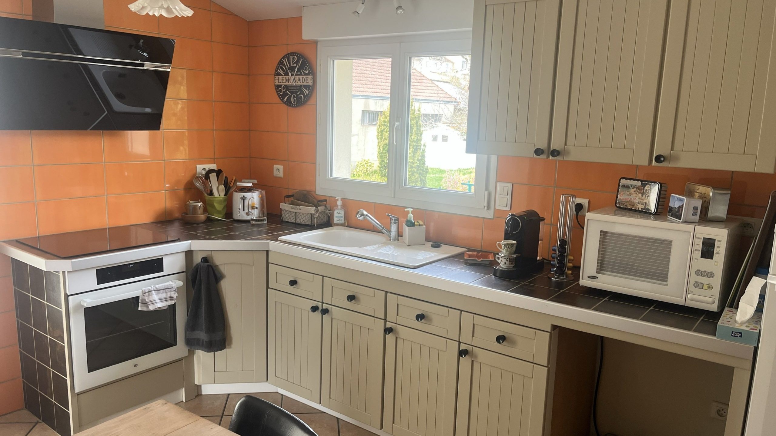 Cuisine grise avec poignée, faïence orange, buffet bois brut ou se trouve actuellement les colonnes.